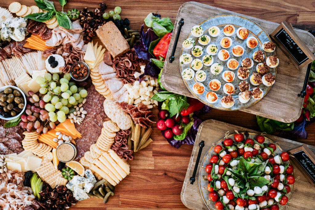 Full charcuterie spread with meats, cheeses, crackers, and fresh produce